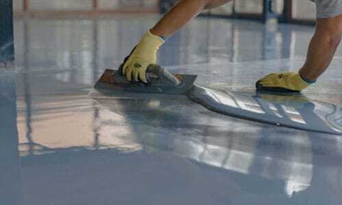 man adds coating to floor
